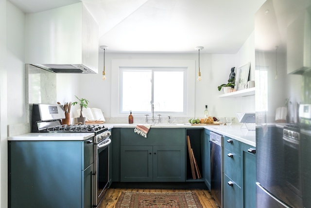 The renovated kitchen is bright and airy with white walls and green cabinetry.