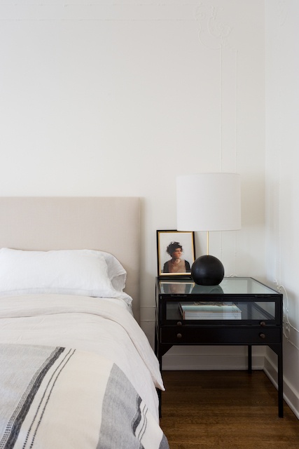 guest bedroom with cream colored headboard and black and white sheets.