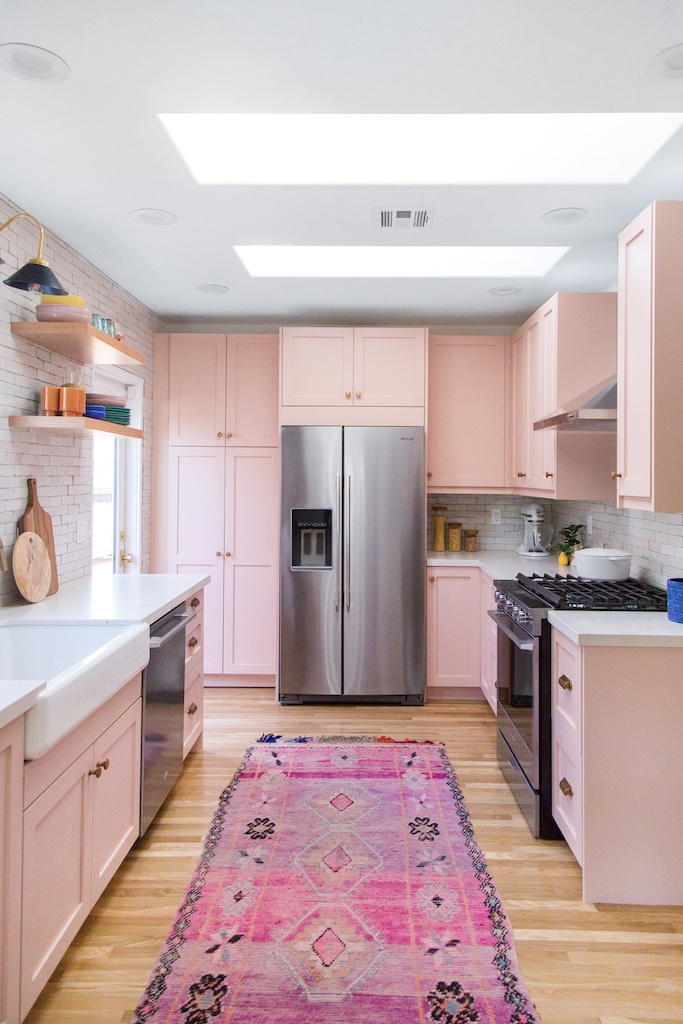 view of a kitchen with pink cabinetry and a stainless steel refrigerator