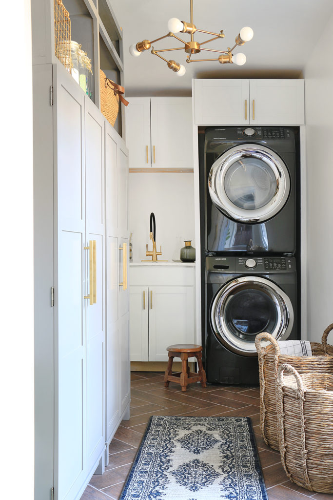 laundry room with white cabinetry, black washer dryer, and a gold chandelier.