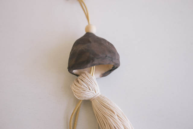 Thread the cord through the top loop on the tassel, and pull until the top part of the tassel is hidden inside the bell-shaped bead.