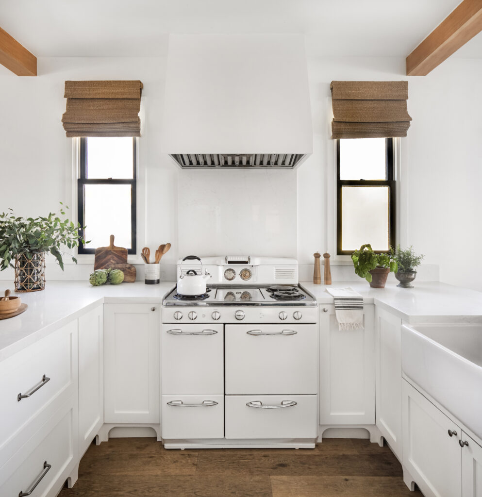 a white vintage oven surrounded by white cabinetry and two matching windows on either side.