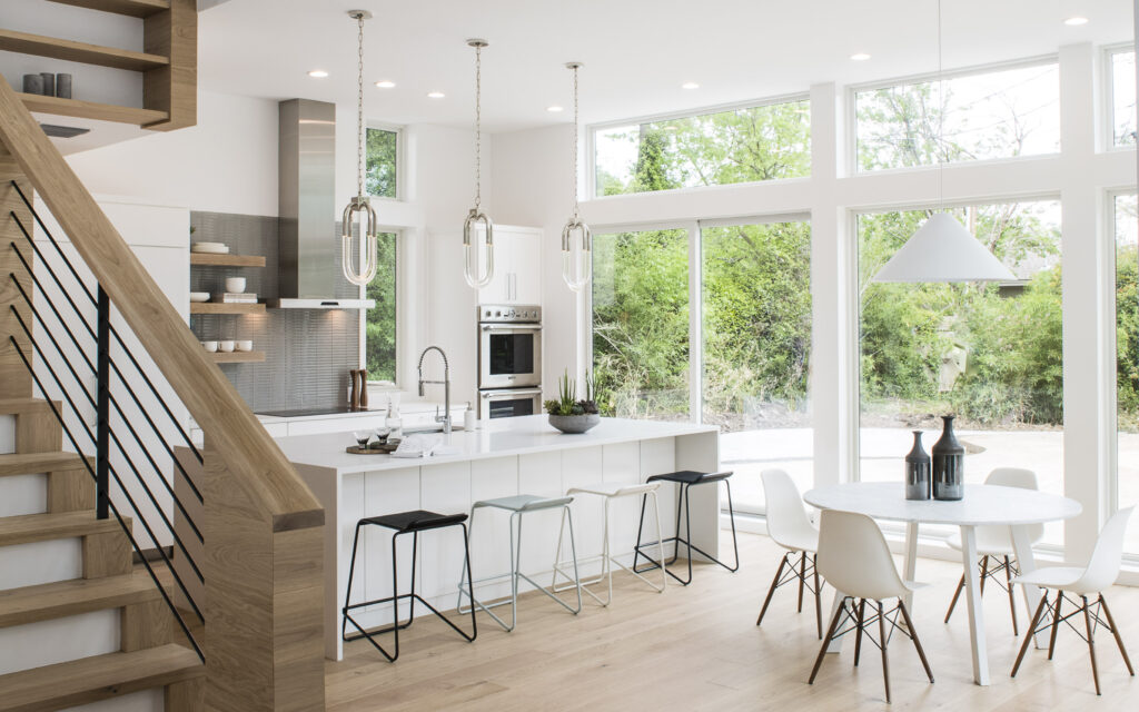white kitchen with large windows and green leaves
