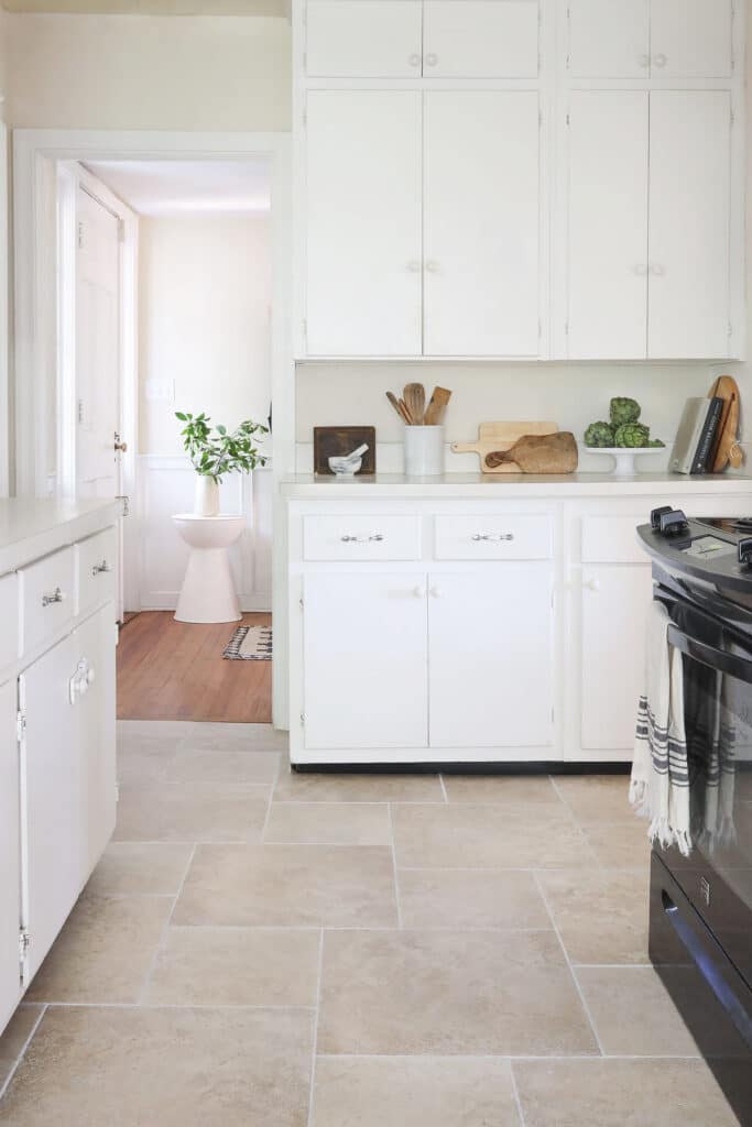 White kitchen with black appliances and sand tile floor