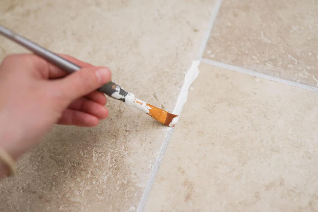 Paint brush going over grout line