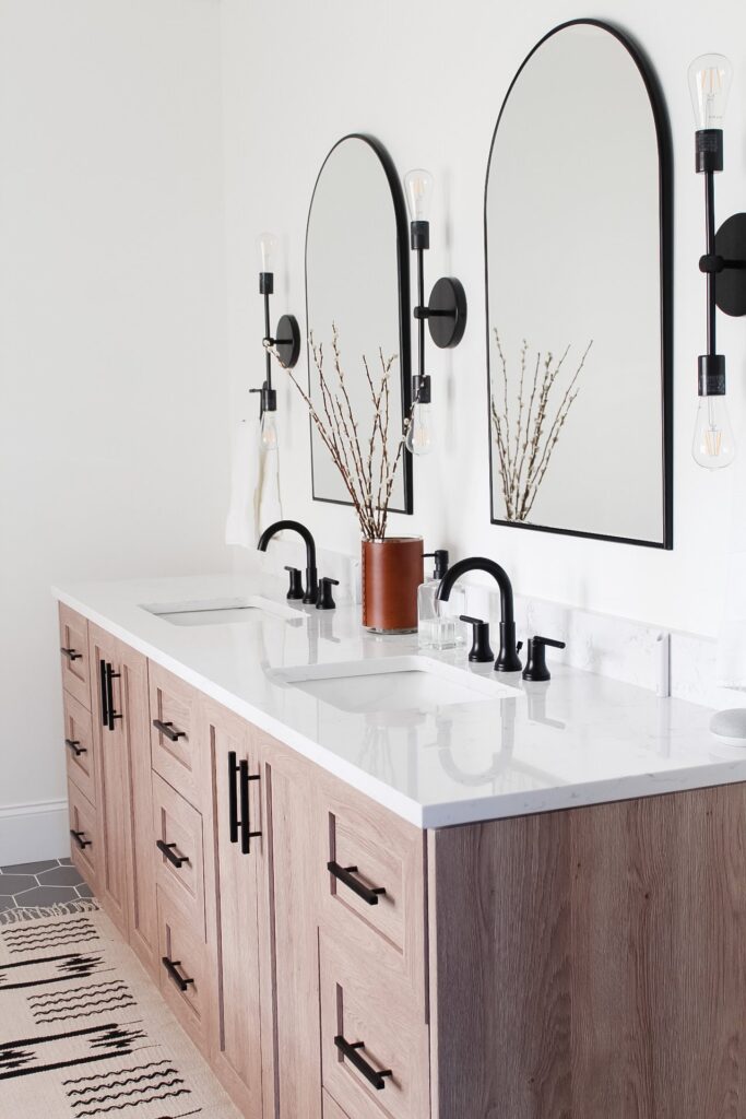 Wood bathroom vanity with arched black frame mirrors