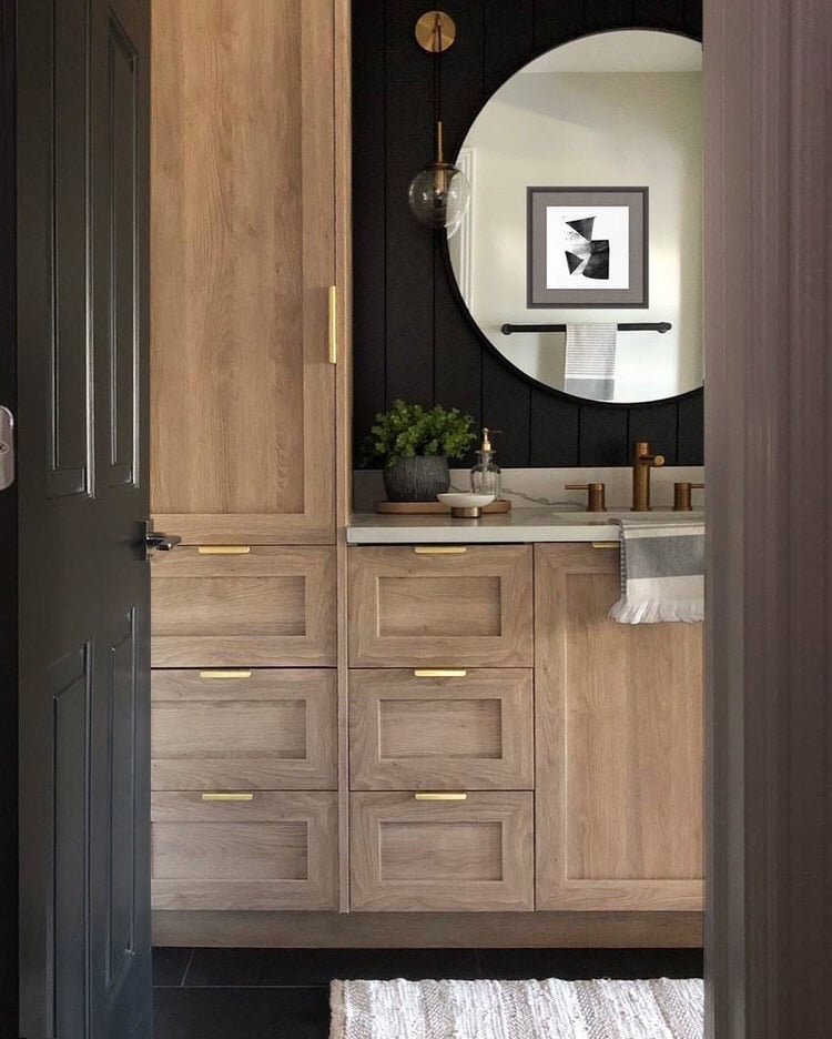 Light wood bathroom cabinets in a black painted space