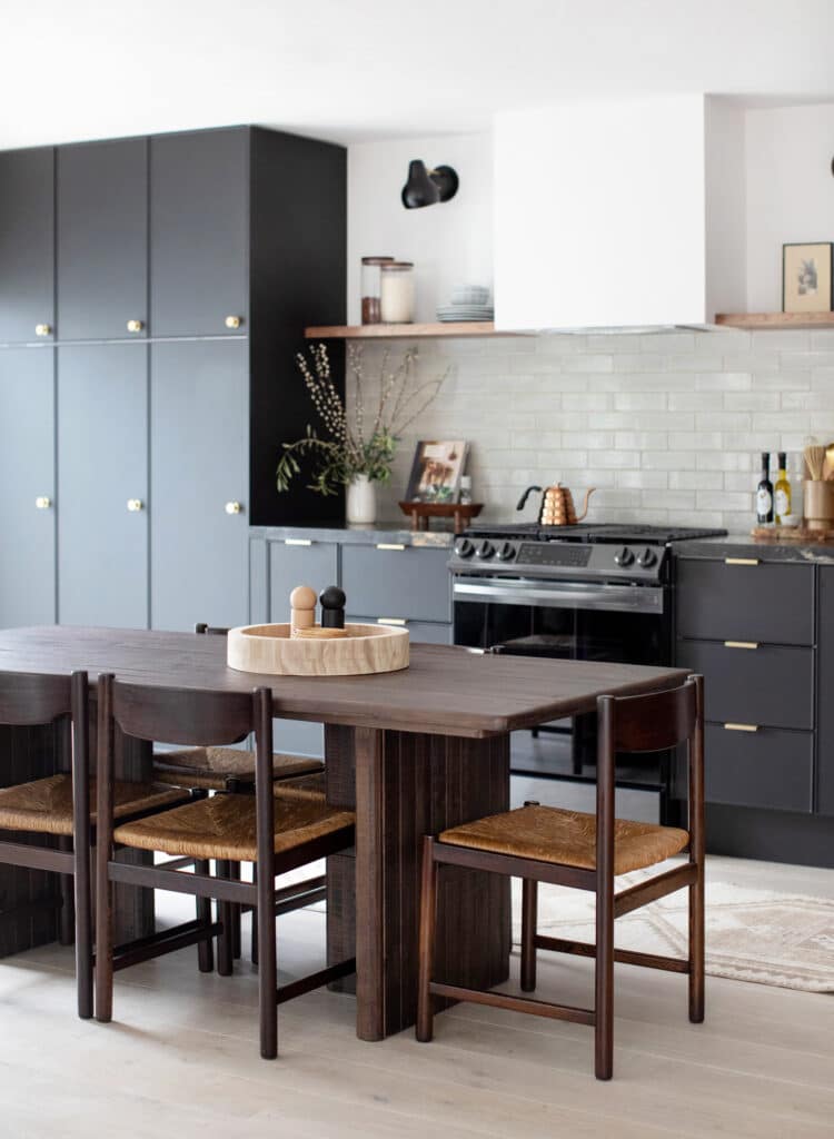 Tall black kitchen cabinets with a dining table in the center of the room