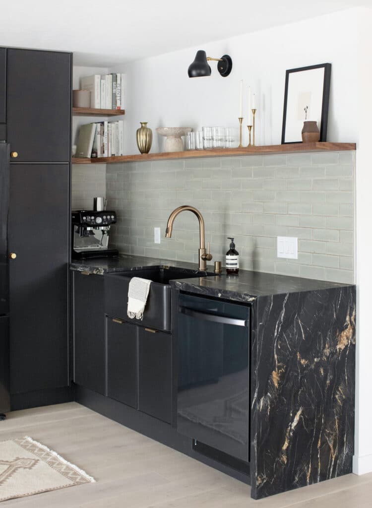 Black granite waterfall counter in a moody black kitchen