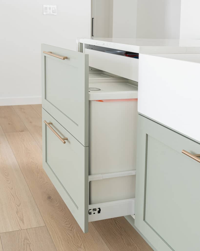 Sage green cabinets featuring a trash pullout