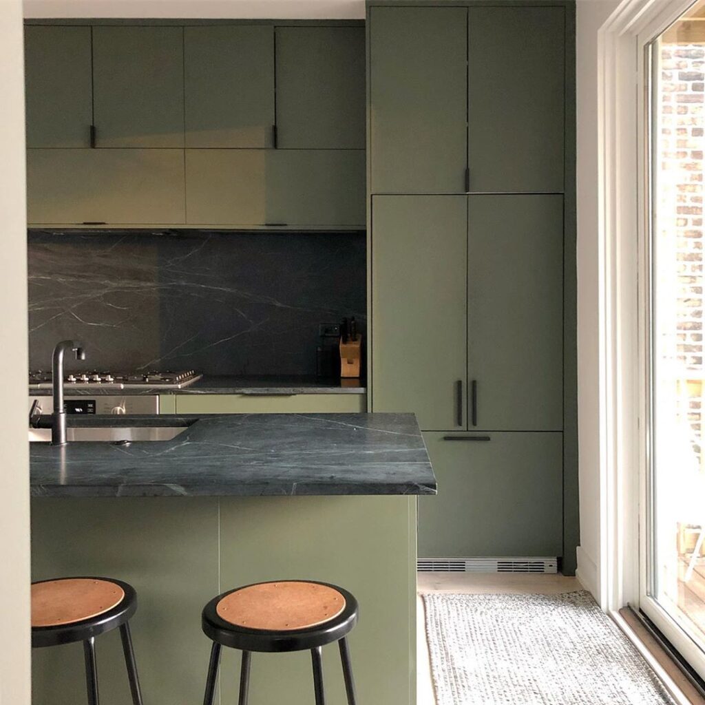 Green kitchen with black counters and backsplash