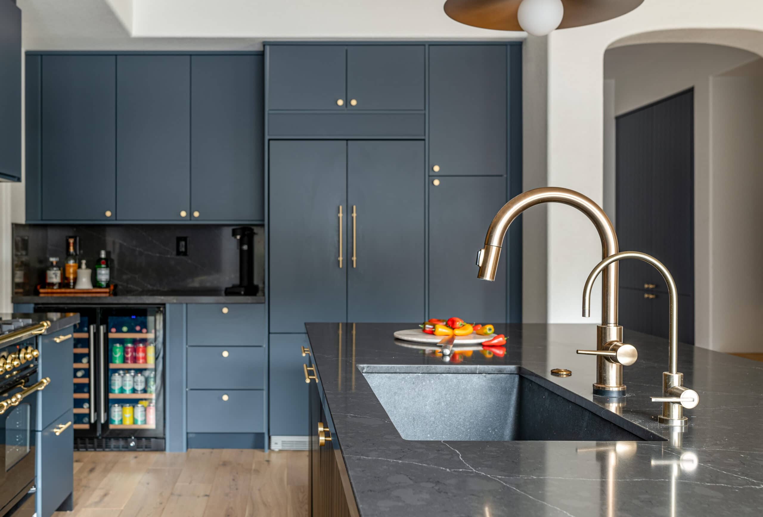 Navy kitchen with wall of cabinets and dark backsplash