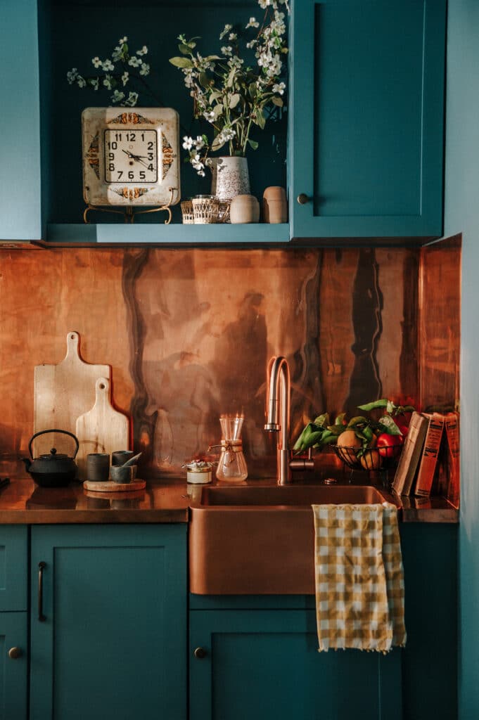 Blue kitchen cabinets with a copper sink and backsplash