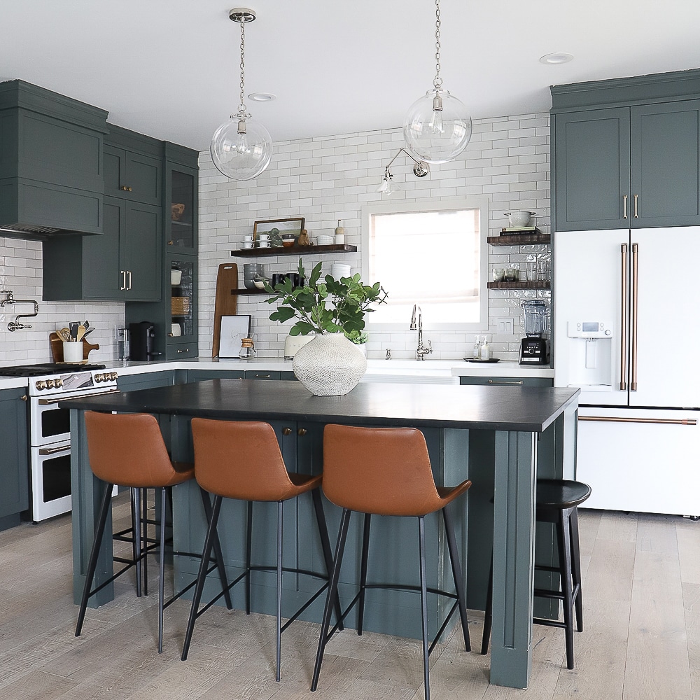 Gray green kitchen with leather bar stools and white appliances