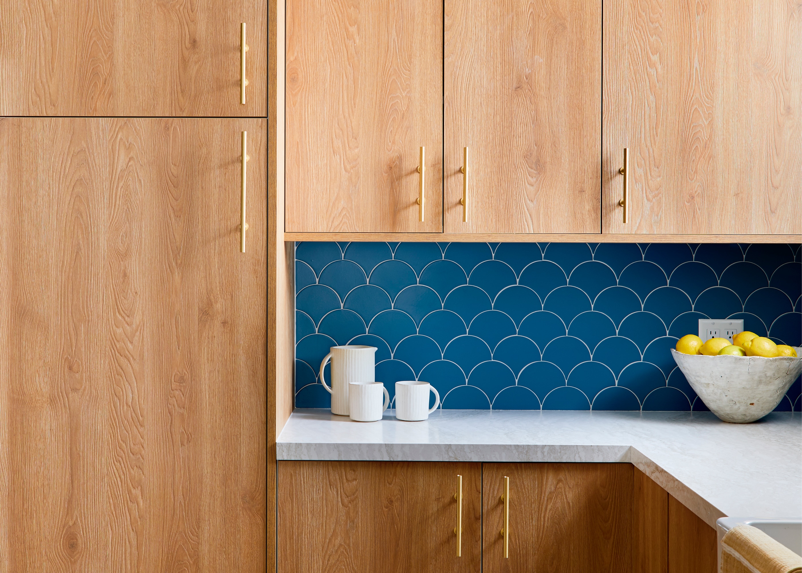 Wood kitchen cabinets with a blue backsplash and white countertops
