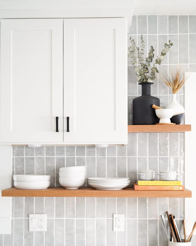 Grey tile backsplash with shelf underneath white upper cabinet