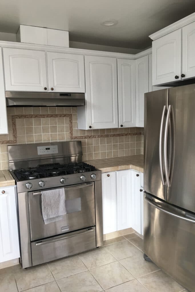 Before view of white cabinets and chrome appliances in a kitchen
