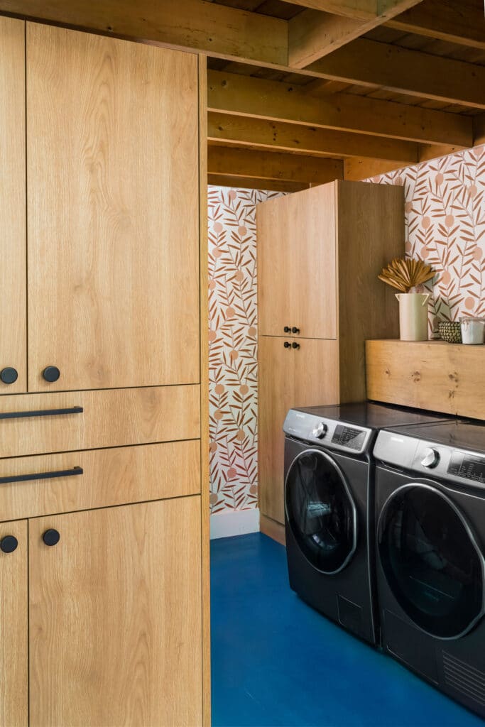 Wood cabinets blue floors and coral wallpaper in a laundry room