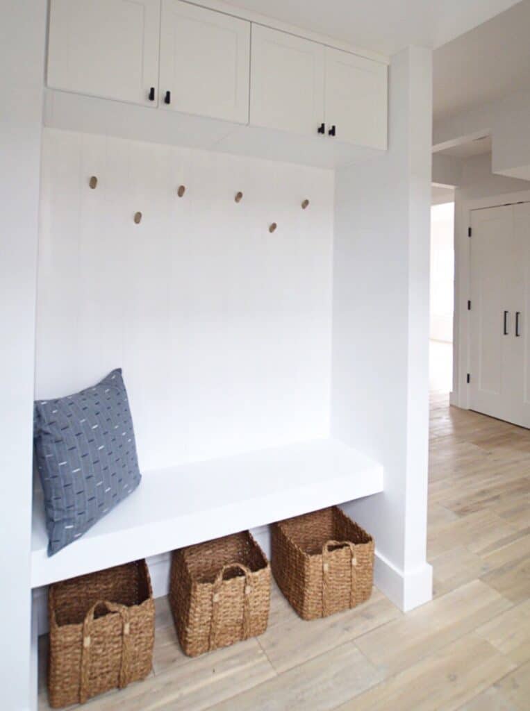 White mudroom cabinets with baskets underneath a bench